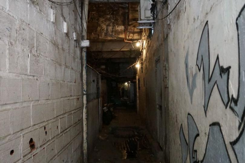Ein langer und dunkler Gang führt in ein ehemaliges Fabrikgebäude, in dem heute Menschen leben.